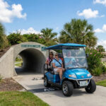 treet-legal LSV with Florida license plate exiting a golf cart tunnel in The Villages, showing compliance with Florida LSV insurance requirements.