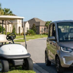 A side-by-side comparison of a white standard golf cart and a metallic silver Neighborhood Electric Vehicle (NEV) on a suburban street, illustrating the physical differences for street legal compliance.